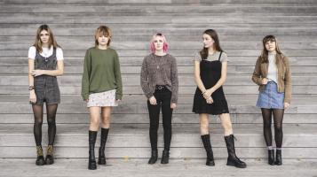 Scottish Fish band members standing in front of a wooden slat wall.