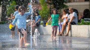 A youth enjoying the splash fountain in a city park
