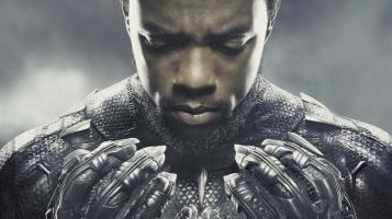 A close up of a dark skinned man wearing a futuristic black armored suit