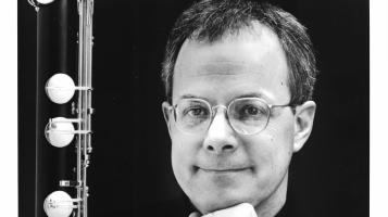 A black and white photograph of a light skinned man bordered by a clarinet