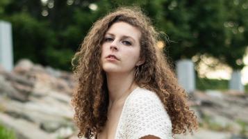 A head shot of a light skinned woman with long curly brown hair