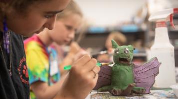 A youth painting a ceramic dragon in a clay studio