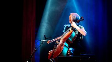 An image of a woman playing cello under blue lights.