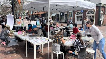 An image of people making art outside under a tent.