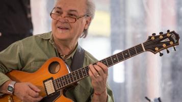 Guitarist Paul Asbell playing guitar and smiling.
