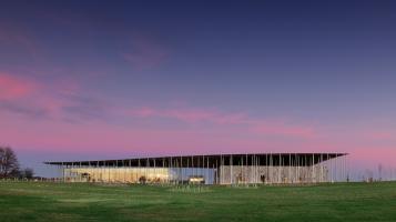 An image of a long, flat building against a cotton candy sunset above a bright green lawn.