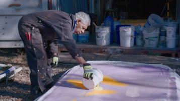 An image of a man preparing a large scale painting.