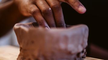 A persons hand making a pinch pot