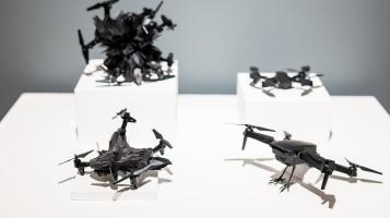 black drone sculptures on a white pedestal.