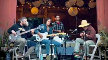a group sitting in a circle playing music in natural light