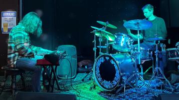 two man band in a dark room with a green light pointed at them.