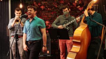 a man singing into a mic with a band around him.