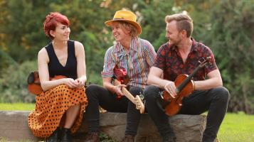 three people sitting on a rock outside