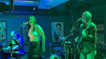 the Moonbirds performing in blue-green, dimly lit bar setting