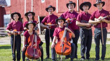 group of fiddlers in matching outfits and hats outside