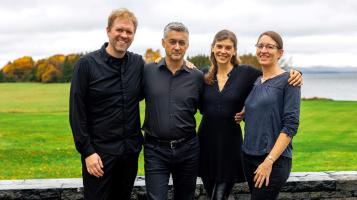 four people standing infront of a green field