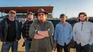 5 caucasion men in western clothing standing in front of Champlain Valley Grandstand