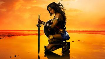 a kneeling Wonder Woman leans on her sword during sunset