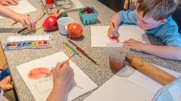 Photo of a child drawing on a table with family members