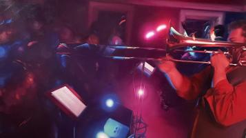 Oil painting depicting an orchestra highlighted in pink and blue.