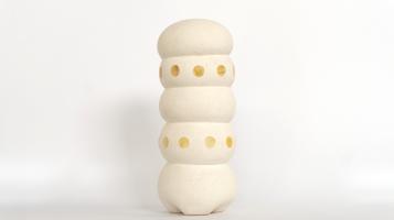 Limestone sculpture of five rounded ovals with three yellow dots on oval 3 and 4