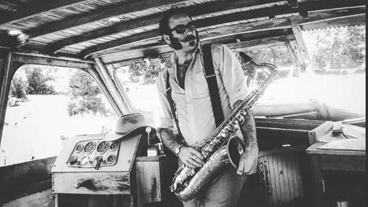 black and white photo of artist holding a saxophone in an abandoned boat