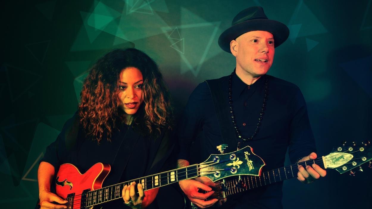 Dwight and Nicole both hold electric guitars.