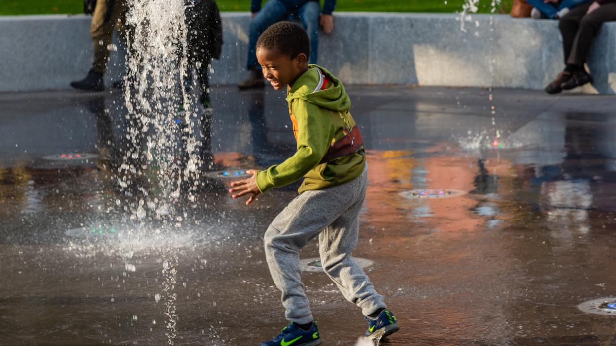 young kid playing in a splash fountain