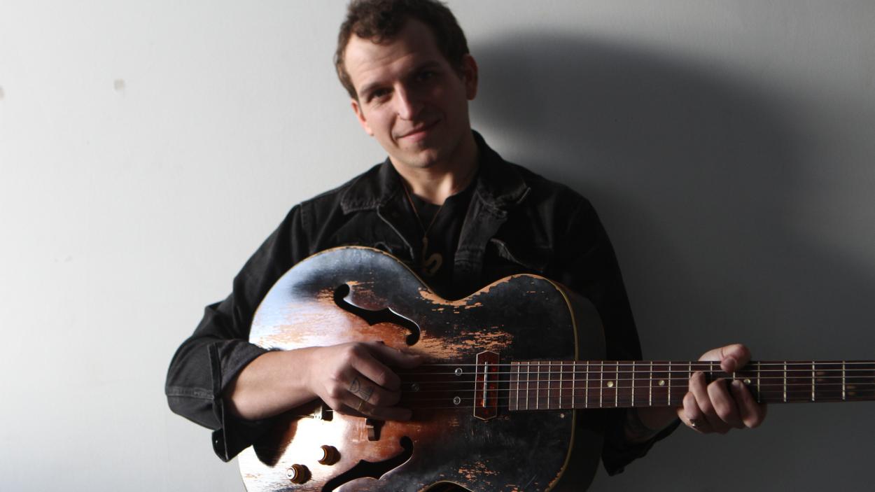 Eric George holds an acoustic guitar.