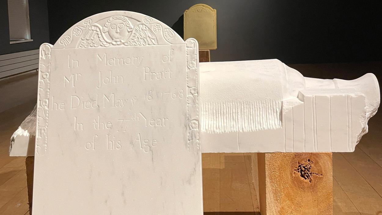 A marble gravestone inspired by the Pratt Slab sits in a gallery setting