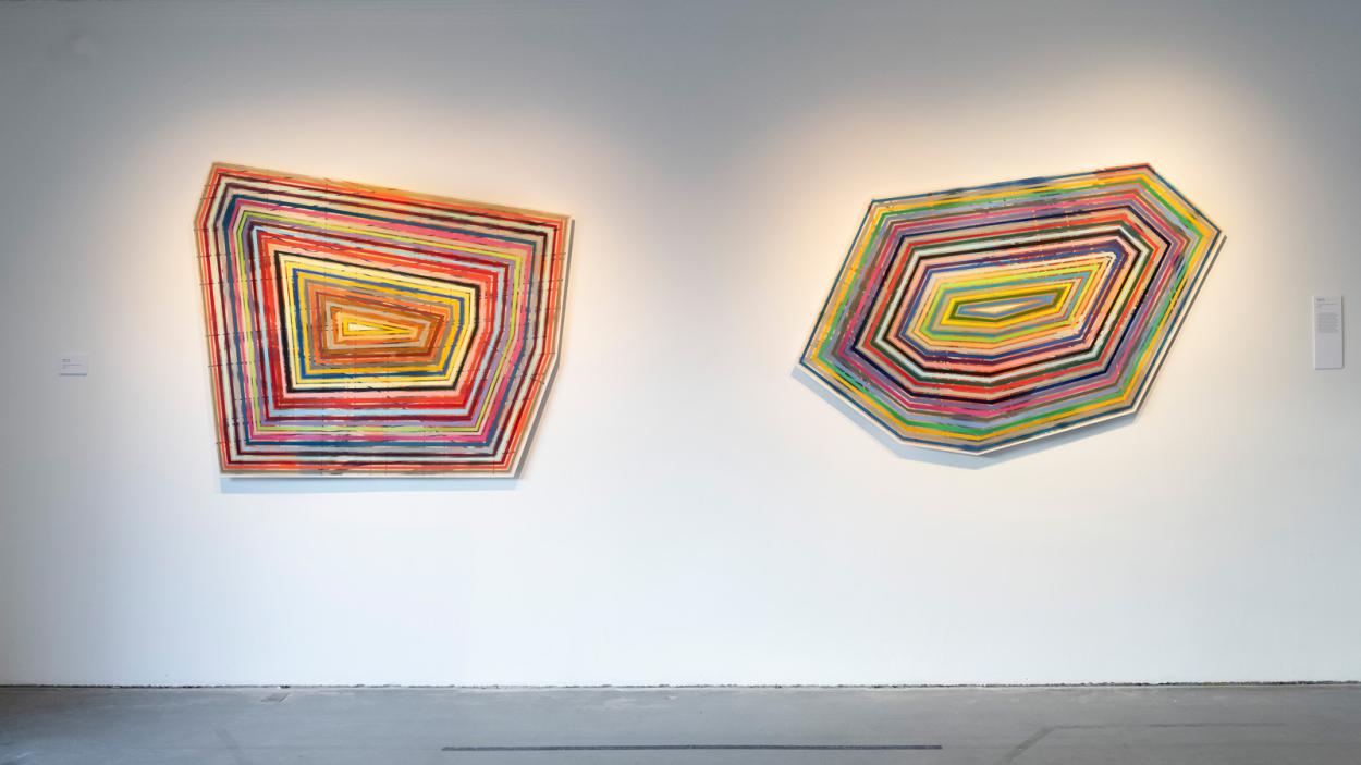 colorful, hypnotic, and repetitious 2-D Geometric shellacked art on a gallery wall