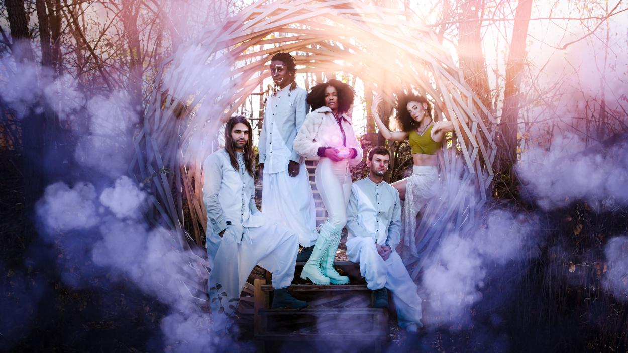 A photo of a group of people wearing white, futuristic clothes, standing in an orb woven from tree branches surrounded by purple clouds