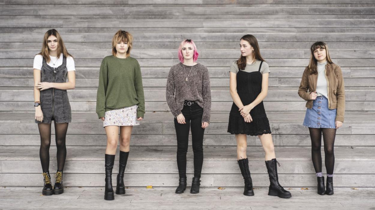 ScottishFish.jpg Scottish Fish band members standing in front of a wooden slat wall.