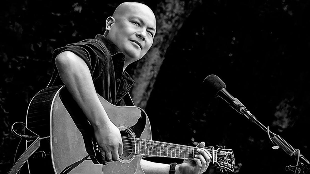 Steve is playing an acoustic guitar on stage