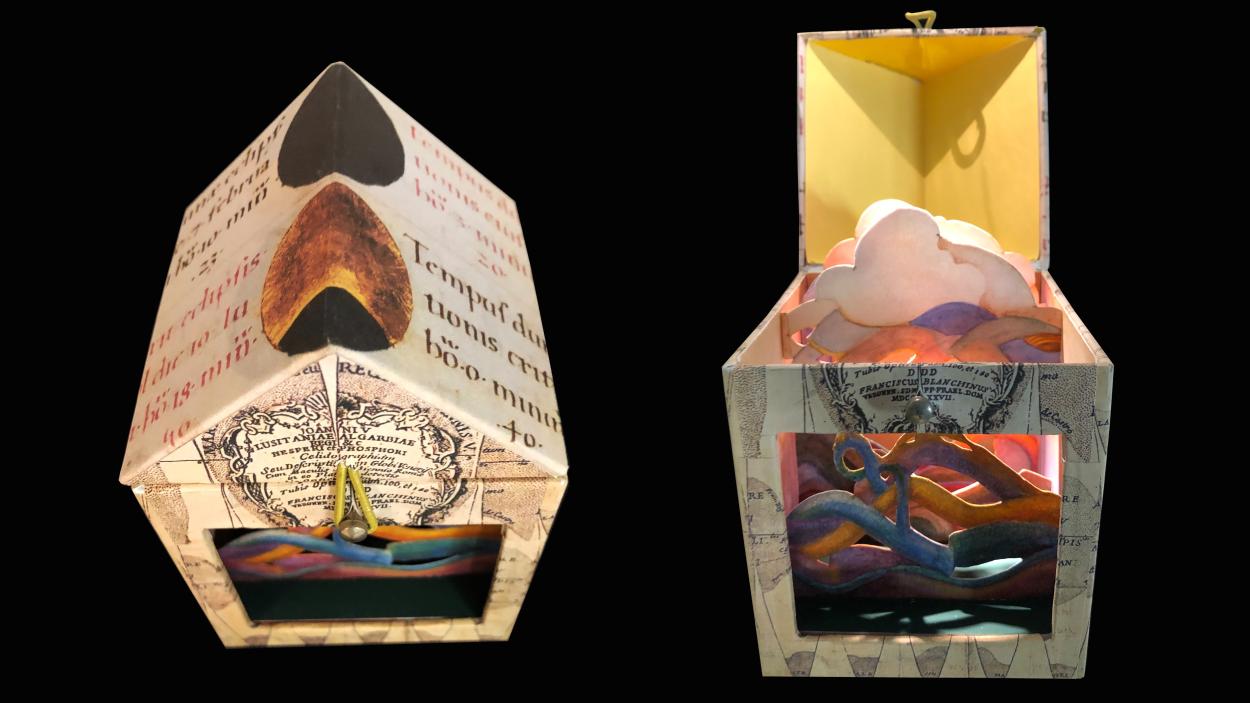 Two small multi colored collaged boxes in the shape of houses against a black background