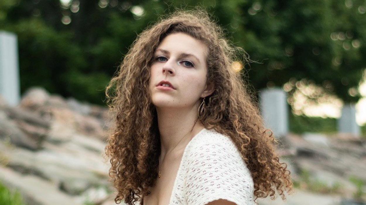A head shot of a light skinned woman with long curly brown hair