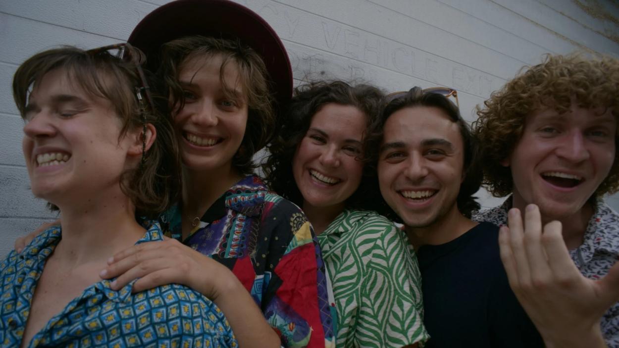 Five people smile, looking at the camera