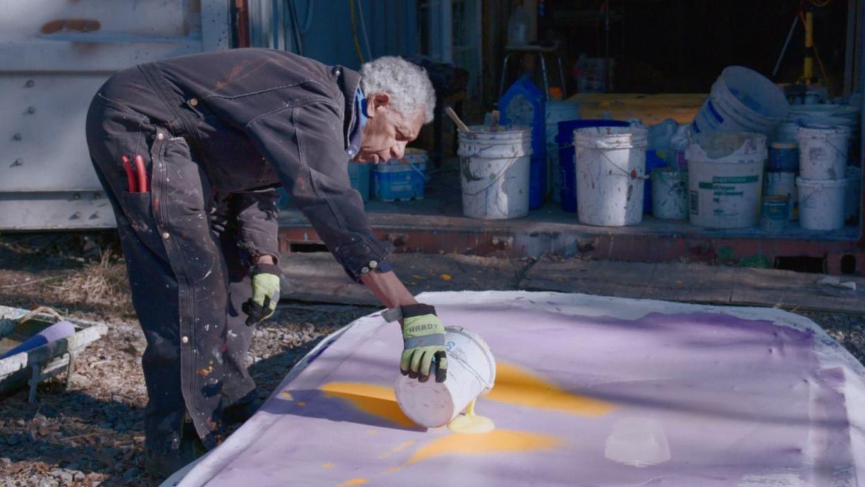 An image of a man preparing a large scale painting.