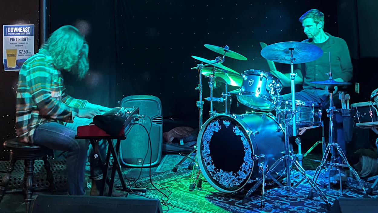 two man band in a dark room with a green light pointed at them.