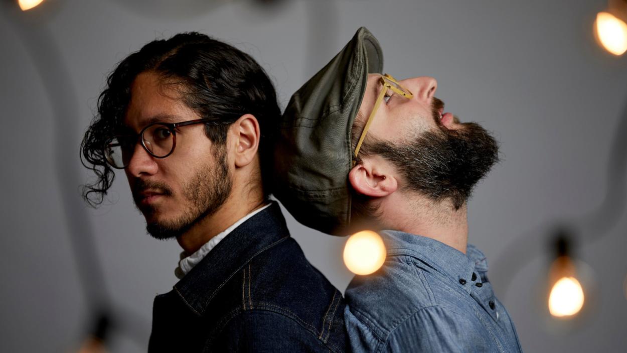 Two men leaning against eachother from a side profile.