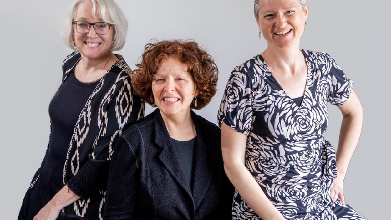 group of three middle aged women with a grey background