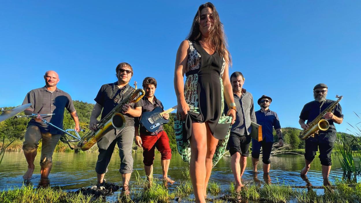 The band holding their instruments standing in swamp land on a beautiful blue sky summer day