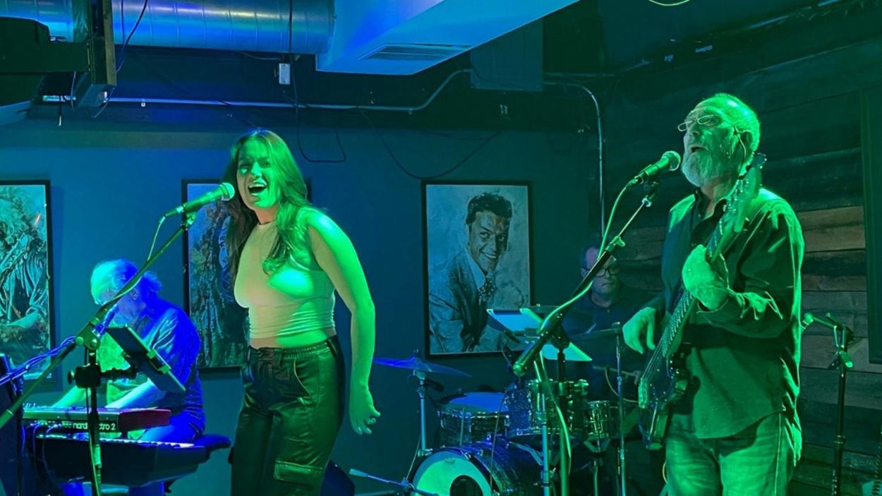 the Moonbirds performing in blue-green, dimly lit bar setting