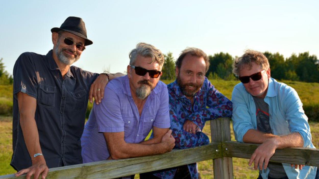 4 guys around a fench on a sunny day