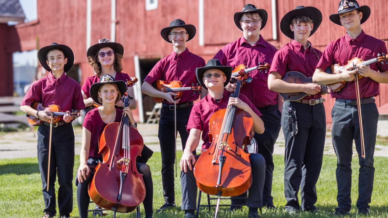 group of fiddlers in matching outfits and hats outside