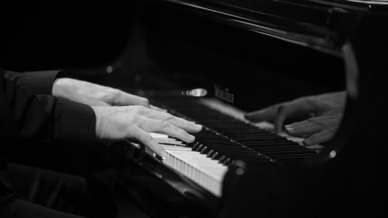 black and white photo of a persons hands playing the piano.