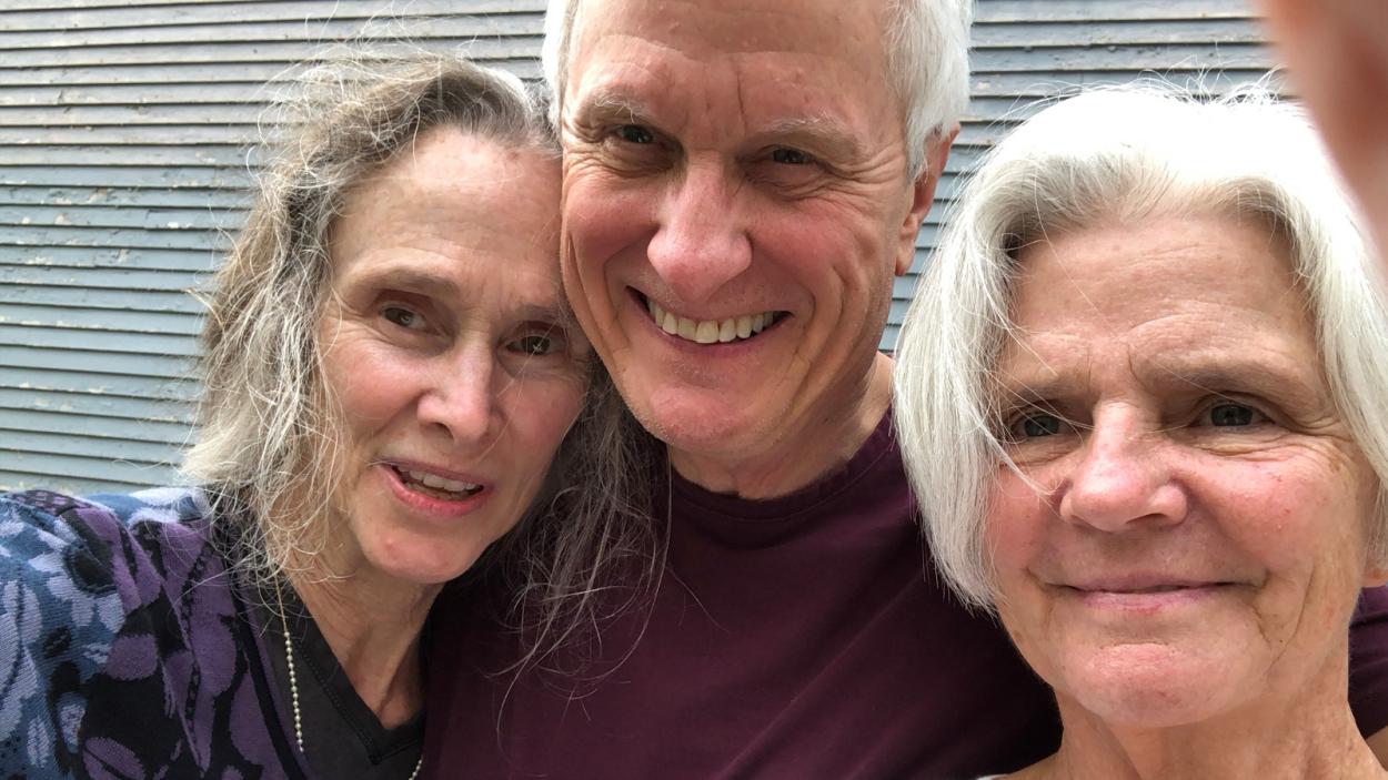 a family of three taking a selfie infront of a garage door.