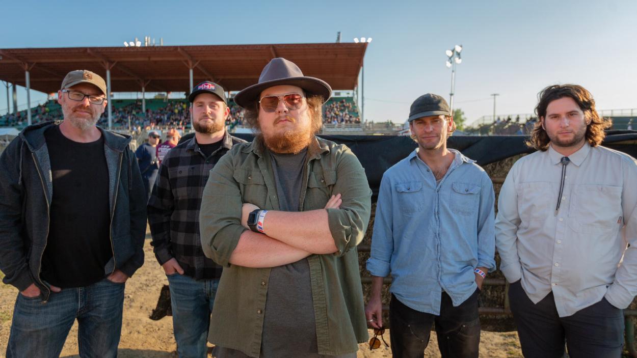 5 caucasion men in western clothing standing in front of Champlain Valley Grandstand
