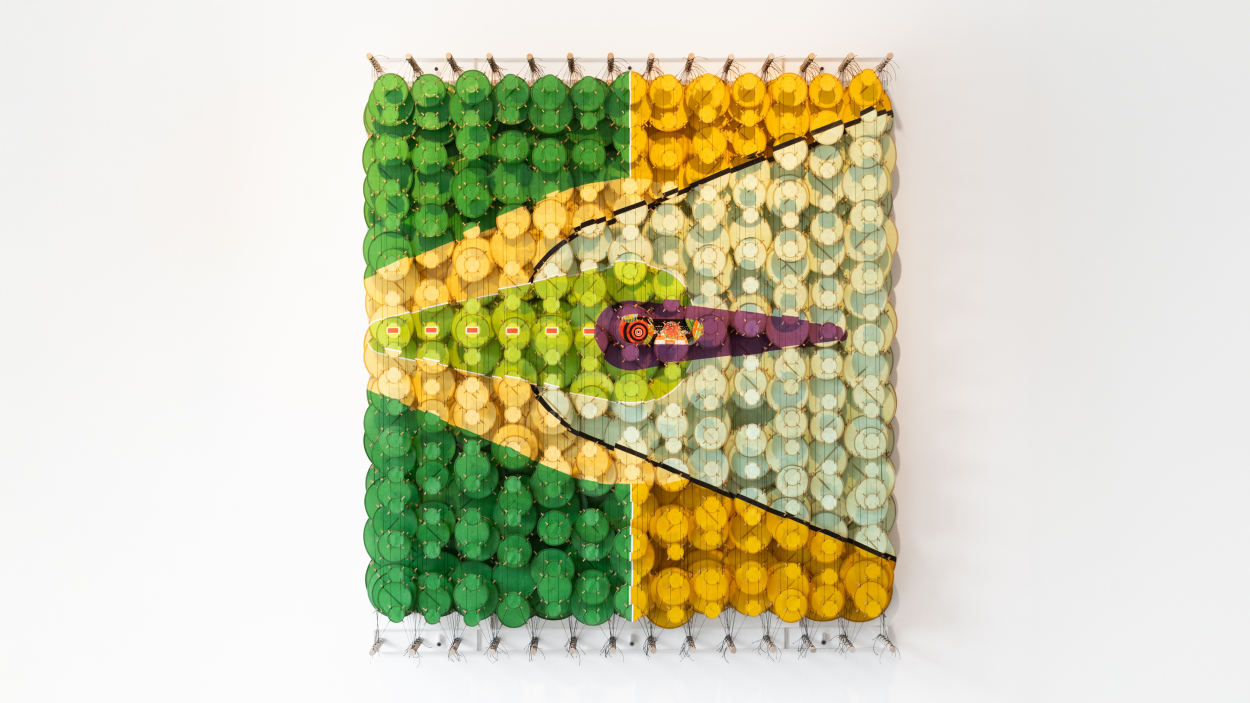 A photograph of an installation by Jacob Hashimoto in the BCA Center Gallery of a grid of colorful discs suspended on strings to form a wall hanging structure