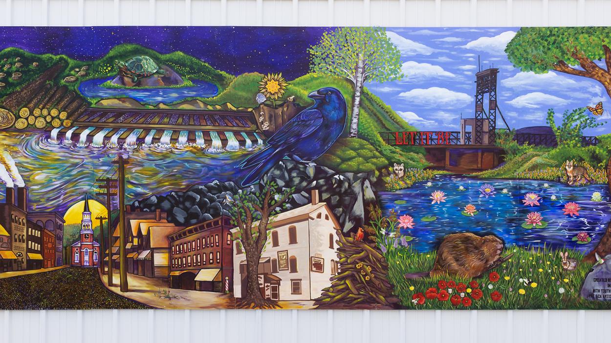 A photograph of a mural, Let It Be: A Cautionary Tale of the Pine St Barge Canal that depicts scenes of nature and overlaid with scenes of industrial development